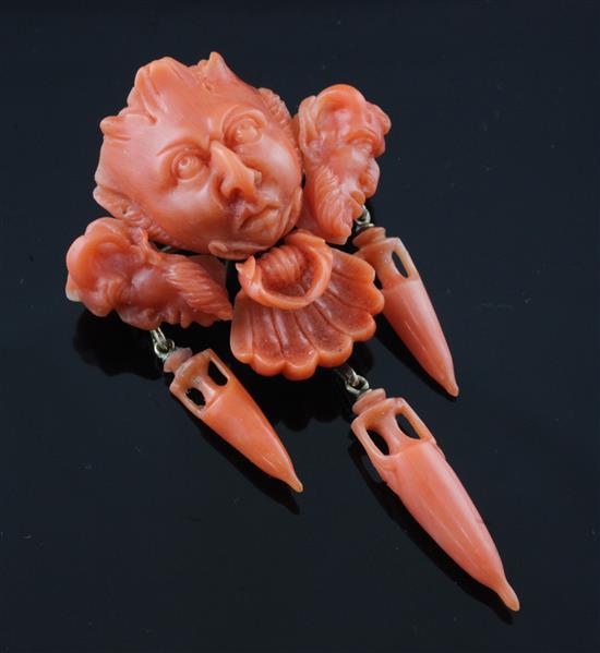 A 19th century gold and coral brooch modelled as three carved satyr masks with three urn shaped drops, 2.5in.